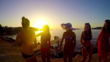 Yavaş hareket beş kız sahilde günbatımı arka planda dans