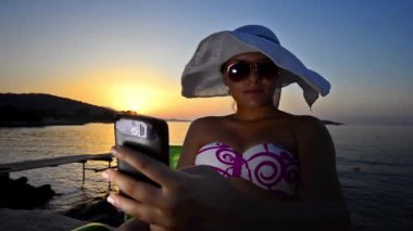 genç kadın selfie smartphone üzerinde okyanus plaj alarak.