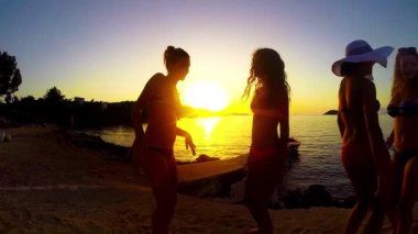 Yavaş hareket beş kız sahilde günbatımı arka planda dans
