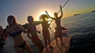 Ağır çekim dört kız sahilde günbatımı arka planda dans