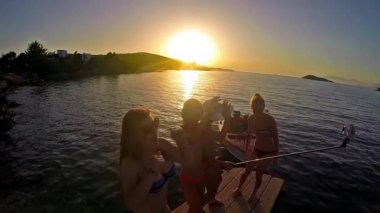 Ağır çekim dört kız sahilde günbatımı arka planda dans