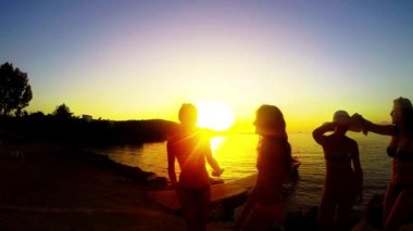 Yavaş hareket beş kız sahilde günbatımı arka planda dans