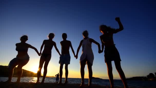 Jóvenes Divirtiéndose Saltando Playa Atardecer — Vídeos de Stock