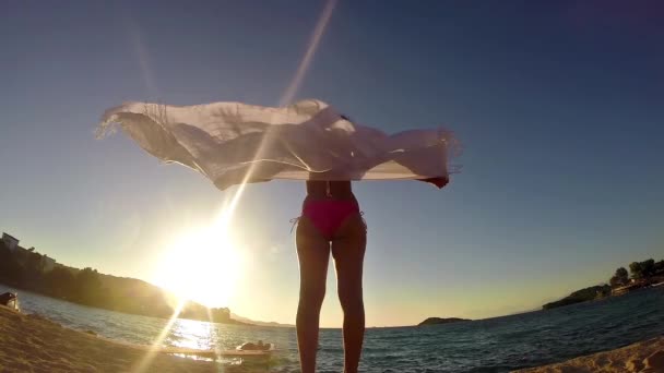 日落背景上挥舞围巾的妇女在海边的慢动作 — 图库视频影像
