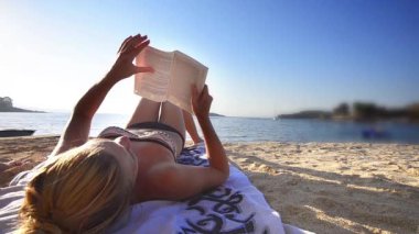 Genç kadın okuma kitabı yaz tatili sırasında plajda