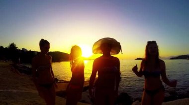 Yavaş hareket beş kız sahilde günbatımı arka planda dans