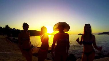 Yavaş hareket beş kız sahilde günbatımı arka planda dans