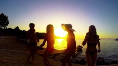 Yavaş hareket beş kız sahilde günbatımı arka planda dans