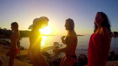 Yavaş hareket beş kız sahilde günbatımı arka planda dans