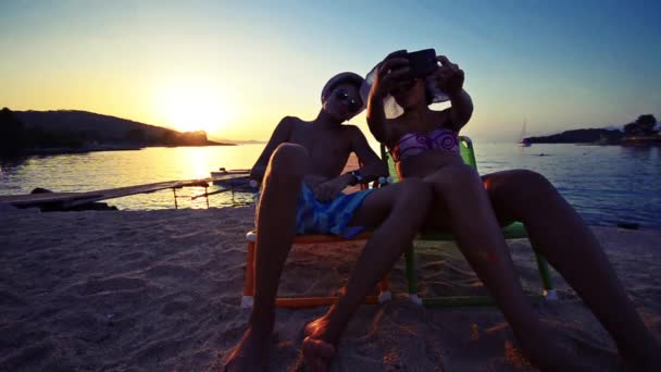 男孩和女孩采取自拍图片在智能手机上日落背景 — 图库视频影像