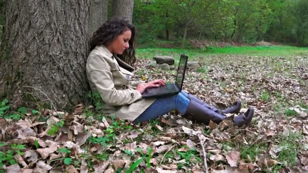 秋季在公园的笔记本电脑上打字的年轻女子 — 图库视频影像