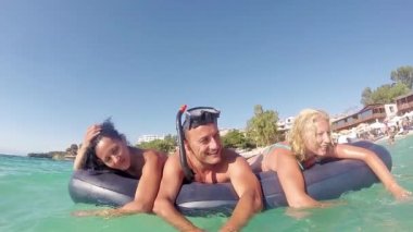 şişme yatak güneşli bir gün, ağır çekim stok video tutan arkadaşlar denizde yüzmek