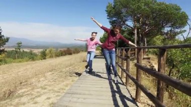 İki anlamlı kızlar eğleniyor dağda uçan uçak oynarken geçit park. Heyecanlı önden görünüm atlama vardır
