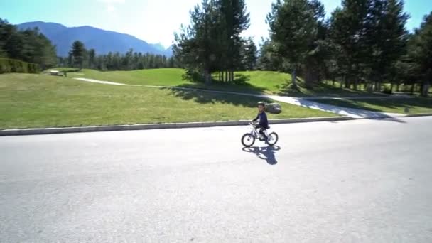 や山々 の背景に空路上少年乗馬自転車 — ストック動画