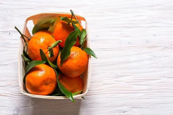 Čerstvé mandarinky se zelenými listy na dřevěný stůl — Stock fotografie