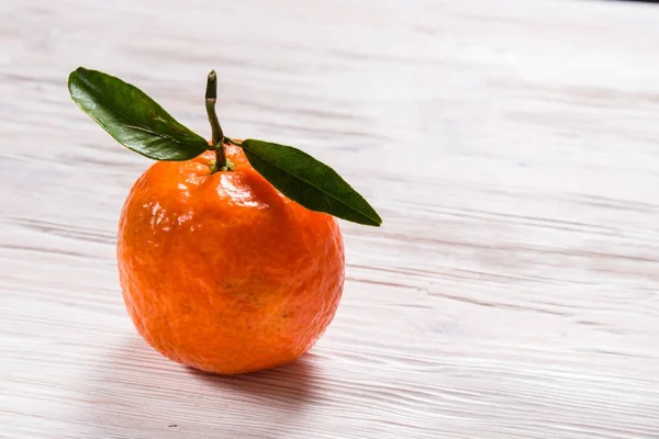 Čerstvé Mandarine se zelenými listy na dřevěný stůl — Stock fotografie