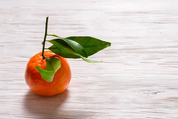 Čerstvé Mandarine se zelenými listy na dřevěný stůl — Stock fotografie