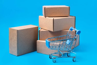 Karton kutular ve mavi arka plan üzerinde alışveriş sepeti çok