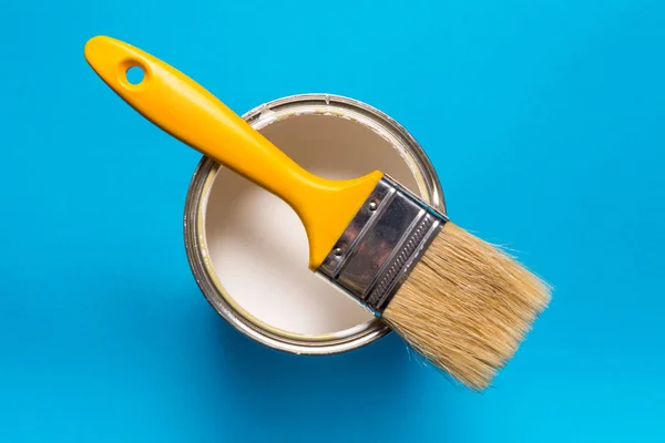 Cepillo y lata de pintura sobre fondo azul — Foto de Stock
