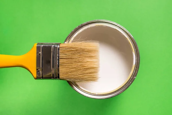 Cepillo y lata de pintura sobre fondo verde — Foto de Stock