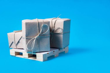 Mavi arka plan, kargo navlun üzerinde küçük palet ve paket kutuları