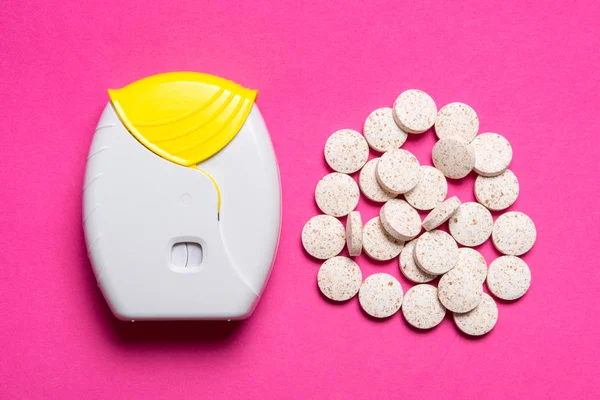 Inalador e comprimidos sobre fundo rosa — Fotografia de Stock
