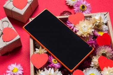 Sevgililer günü hediyesi, akıllı telefon ve çiçek kutusu üzerinde kırmızı zemin hazırlama