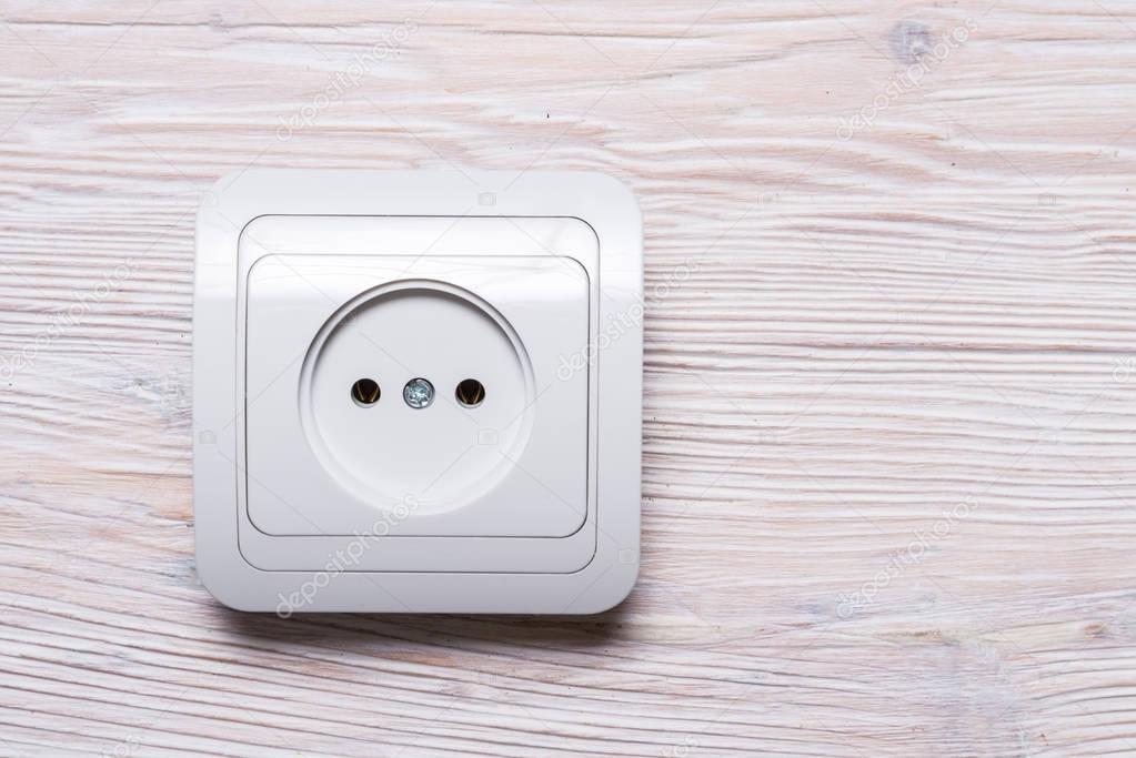 White electricity socket on wood background