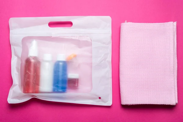 Set of travel bottles and towel in plastic bag — Stock Photo, Image