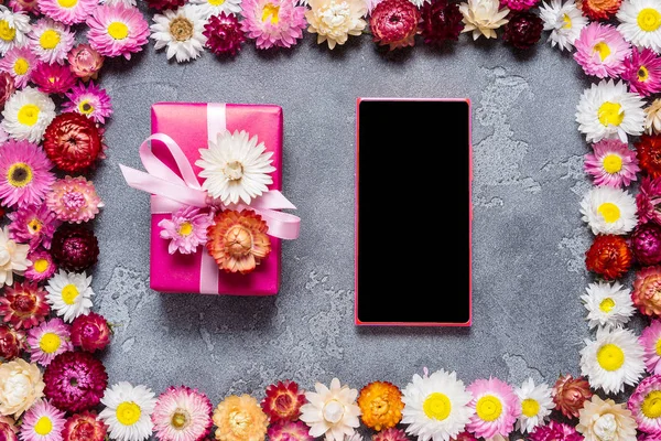 Smart phone and gift box on floral background