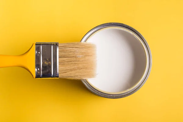 Lata de pintura blanca con vista superior del pincel sobre fondo amarillo . — Foto de Stock