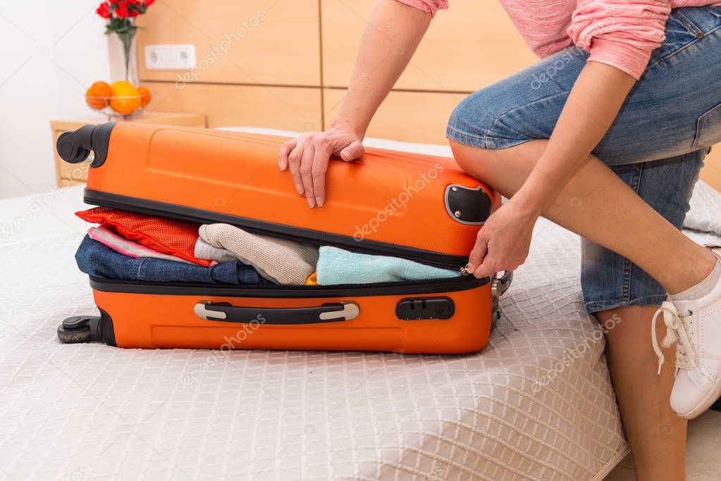 Woman having problem with closing suitcase