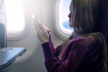 Genç kadın uçak mobil smartphone kullanarak