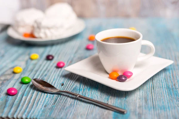 Чашка кофе и цветные конфеты на синем столе — стоковое фото