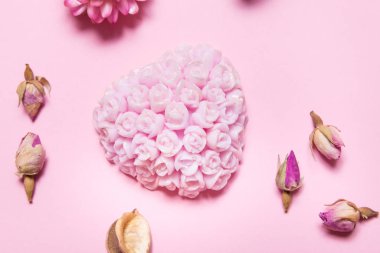 Pembe arka planda gül yağı içeren el yapımı sabun.