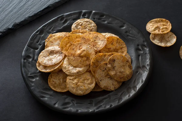 Massor av ris chips i svart keramik skål — Stockfoto