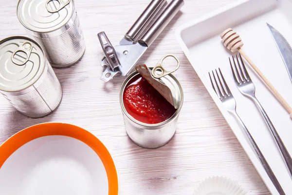 Opened tin can with canned tomatoes, on wooden kitchen table — 스톡 사진