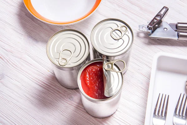 Lata aberta com tomates enlatados, na mesa de cozinha de madeira — Fotografia de Stock