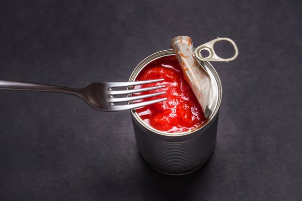 Opened tin can with canned tomatoes, on black background — 스톡 사진