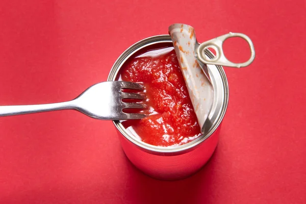 Öppnad burk med konserverade tomater, på röd bakgrund — Stockfoto