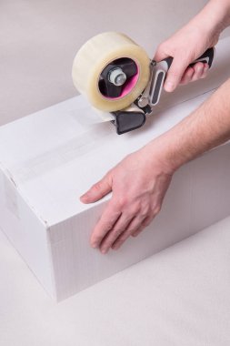 İşçi bant dağıtıcısıyla çalışıyor, karton sanayi kutusunu kapatıyor