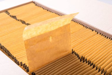 Karton kutuda bir sürü kahverengi kağıt posta zarfı var.