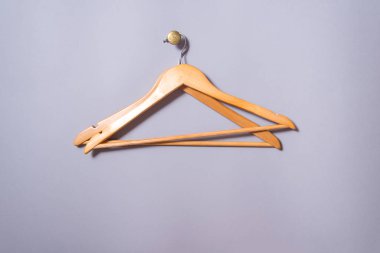 2 boş ahşap kaplama elbise askısı gri duvarda asılı.