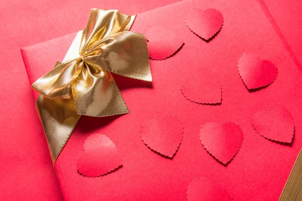Red gift box with gold ribbon on red background, copy space