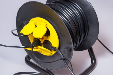 Siyah elektrik uzatma kablosu dört çoraplı bir makarada.