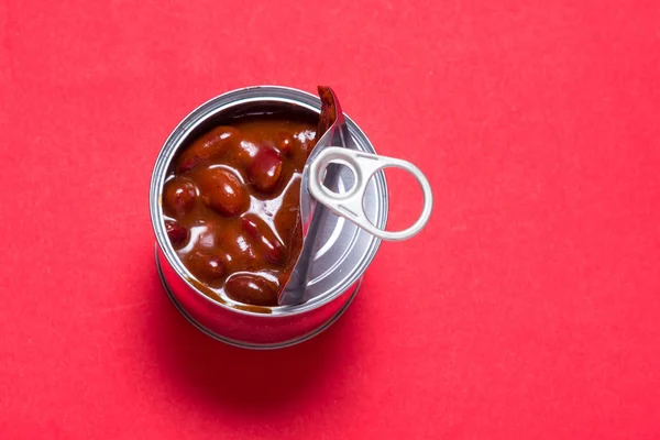 Öppnad tenn burk, burk röda chili varma bönor på röd bakgrund — Stockfoto