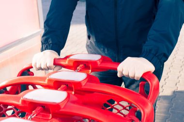 Adam süpermarkette alışveriş arabasıyla gezer, halkla ilişkiler için lateks eldiven kullanır.