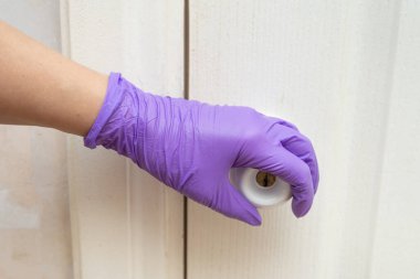 Ellerim kapı kolunu lateks eldivenle tutuyor.