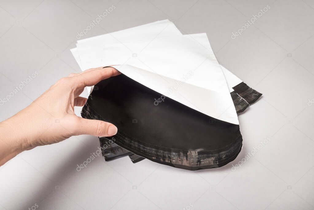 Woman hands working with white polythene envelopes on grey backg