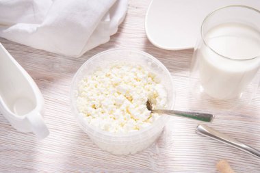 Ahşap masada plastik kavanozda beyaz süzme peynir.